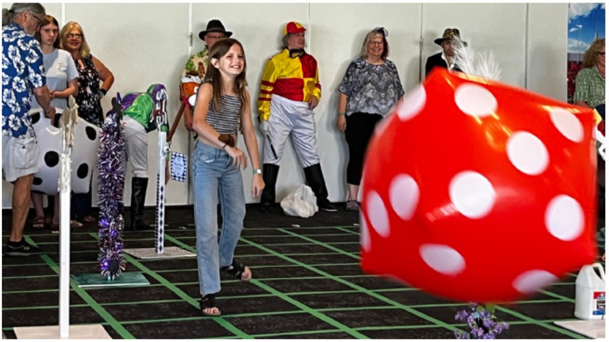 A young guest tosses a giant inflatable die during Derby Day games